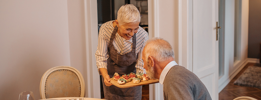 Image of senior woman serving her senior husband some appetizers on a tray